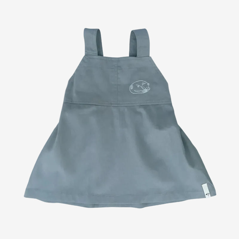 Blue denim pinafore dress with a small logo on a white background