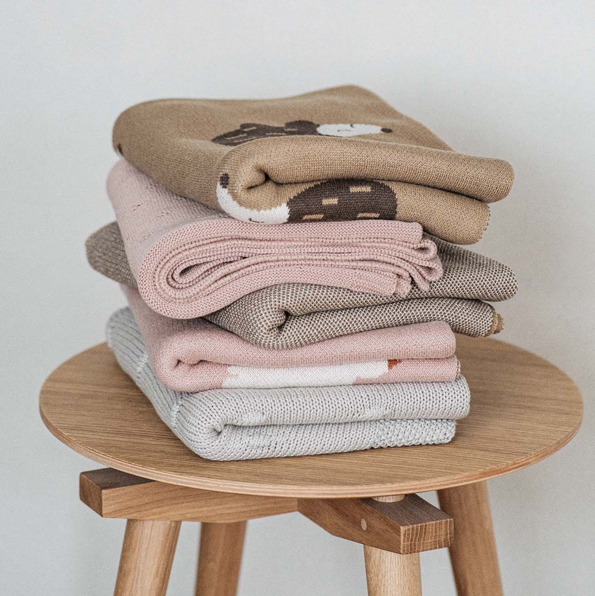 Fine knitted cotton blankets on wooden oak chair in jacquard knitting technique