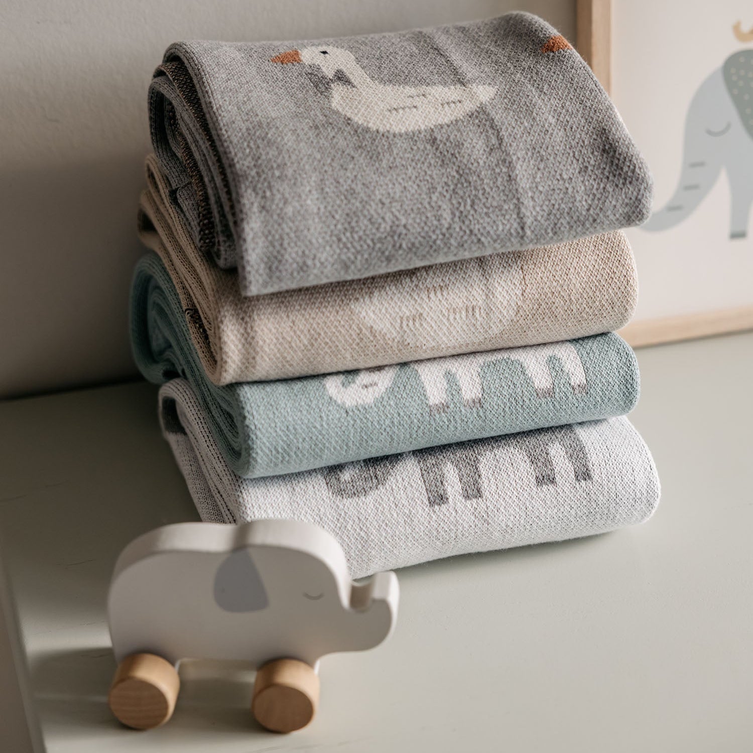 Stack of baby blankets with cartoon designs on a neutral background