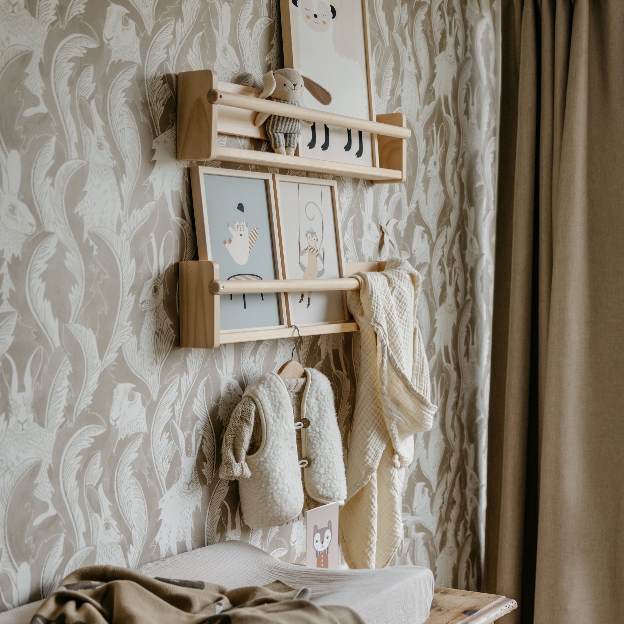 Nursery room with changing table, baby clothes, and wall art.
