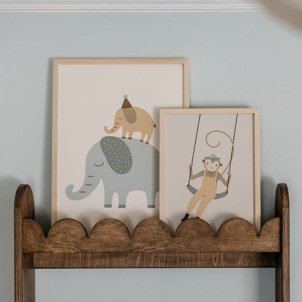 Wooden shelf with framed illustrations of elephants and monkeys against a light blue wall.