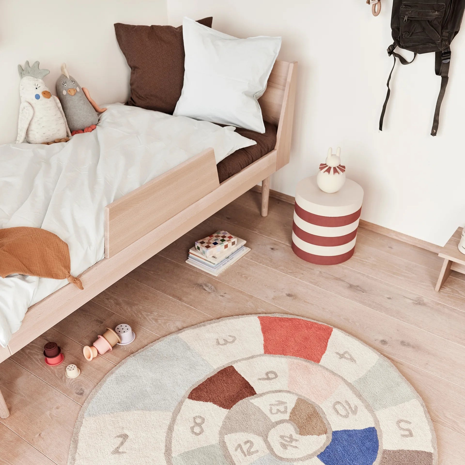 Round multicolored rug with numbers on a wooden floor in a bedroom.