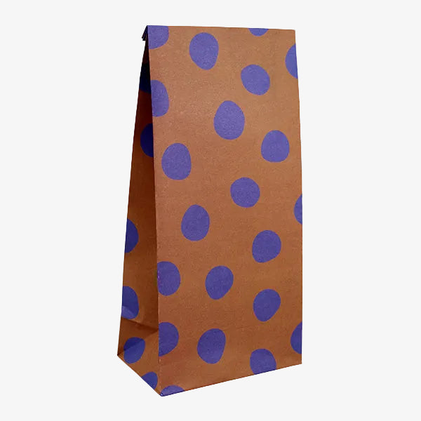 A brown kraft paper party bag with a pattern of large purple polka dots, shown on a plain white background.