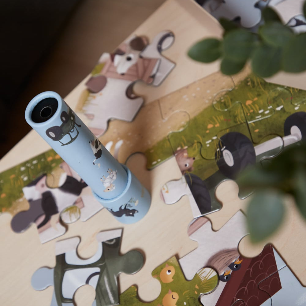 Partial puzzle with cartoon characters on a wooden surface, accompanied by a toy flashlight.