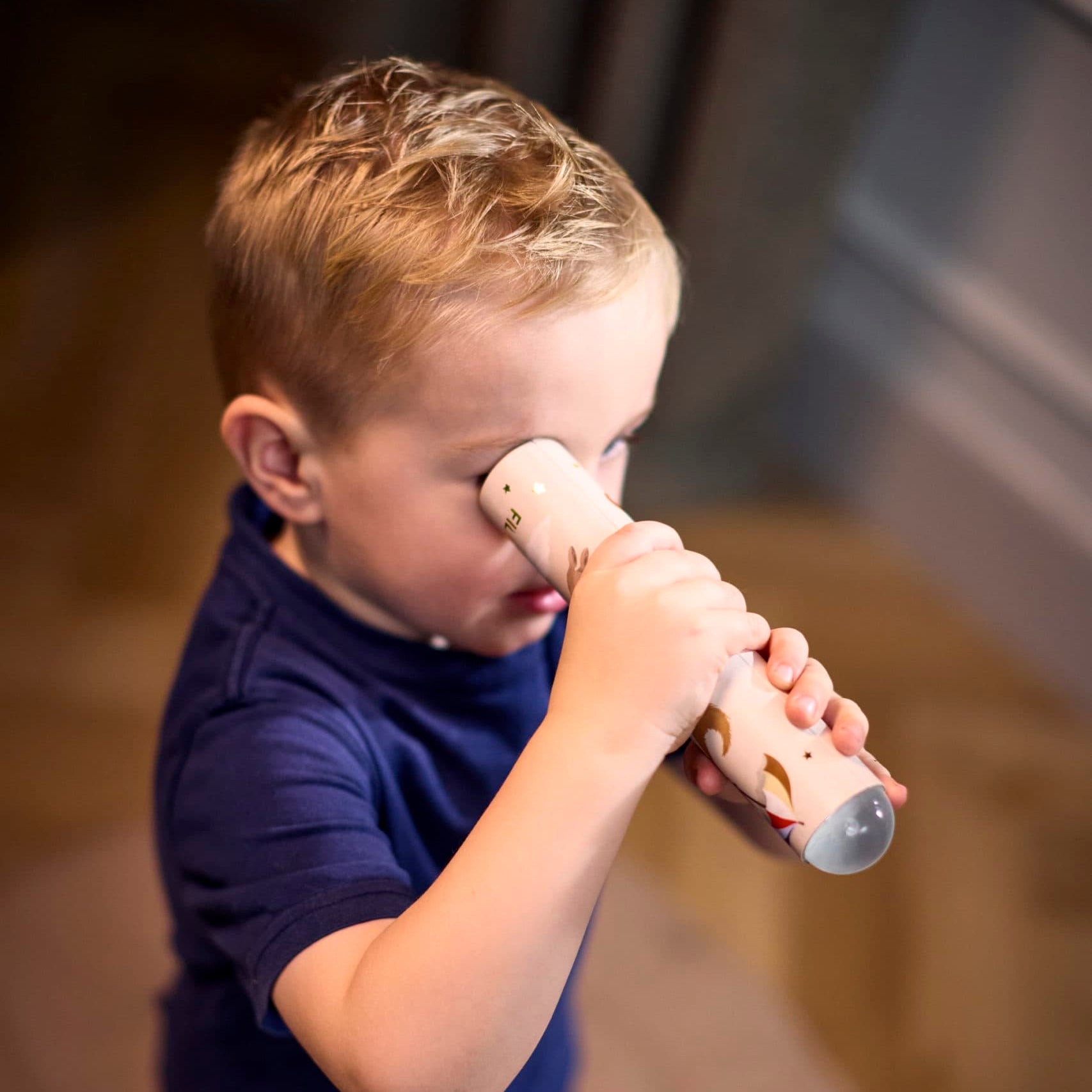 Child holding a toy microphone close to their face indoors 