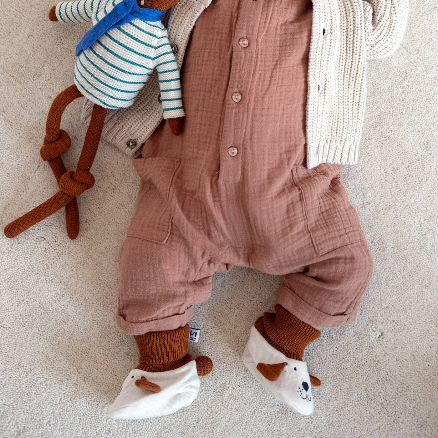 Baby lying on a carpet with a stuffed toy next to them