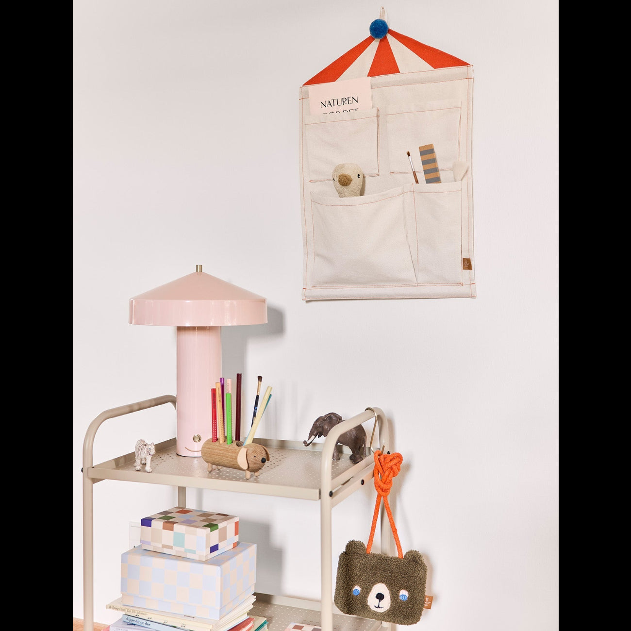 Children's desk with lamp, books, and toys against a white wall