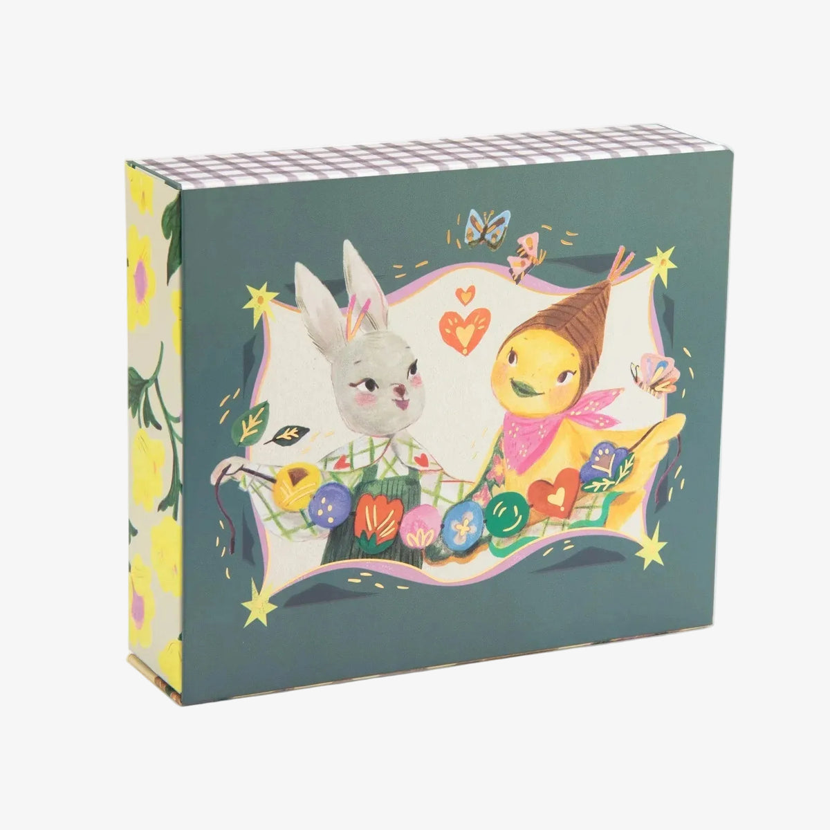 A decorative product box featuring an Easter-themed illustration with a white rabbit and a yellow bird character surrounded by colorful eggs, hearts, stars, and butterflies on a dark teal background. The box is shown at a three-quarter angle on a clean white background.