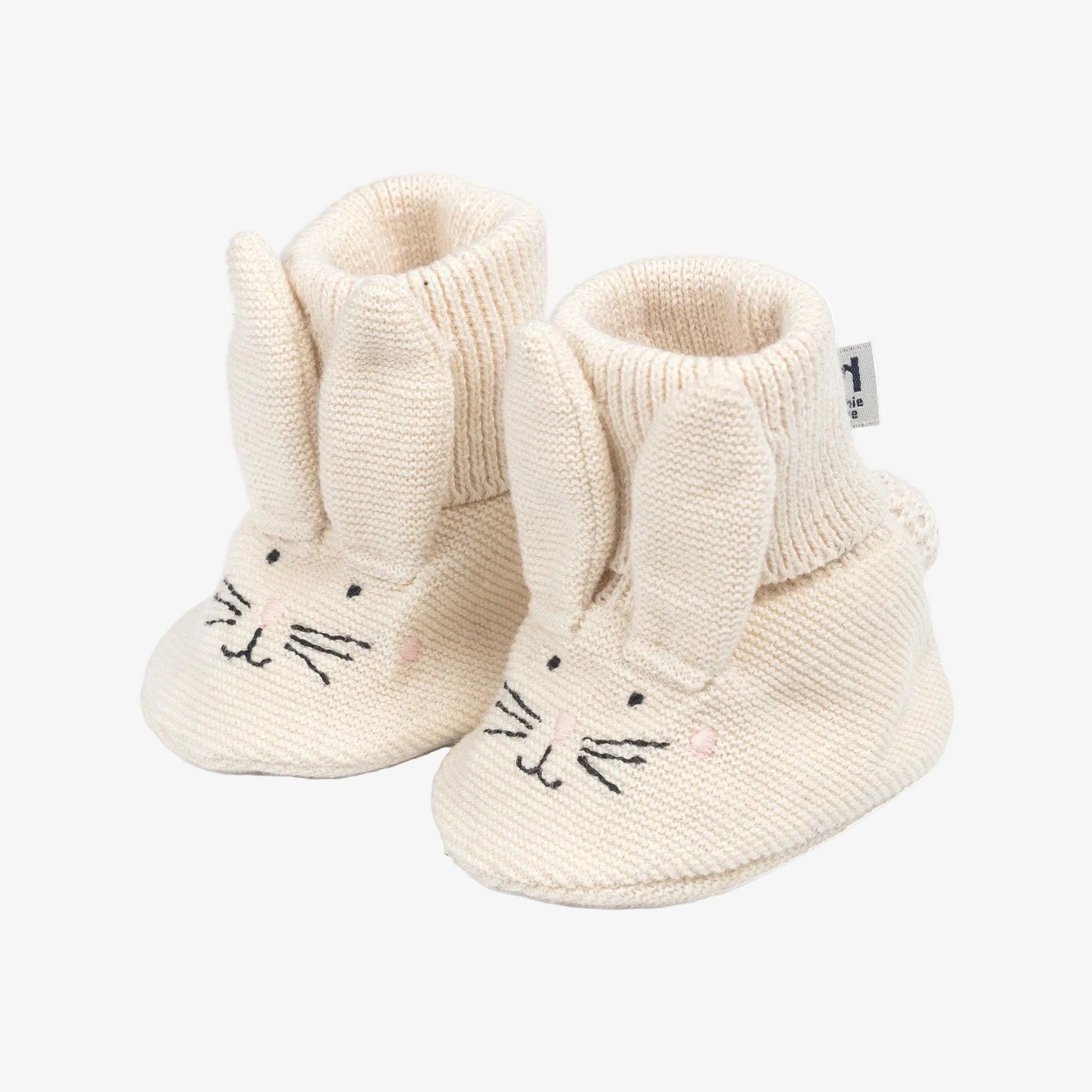 Pair of cream-colored baby booties with bunny design on a white background