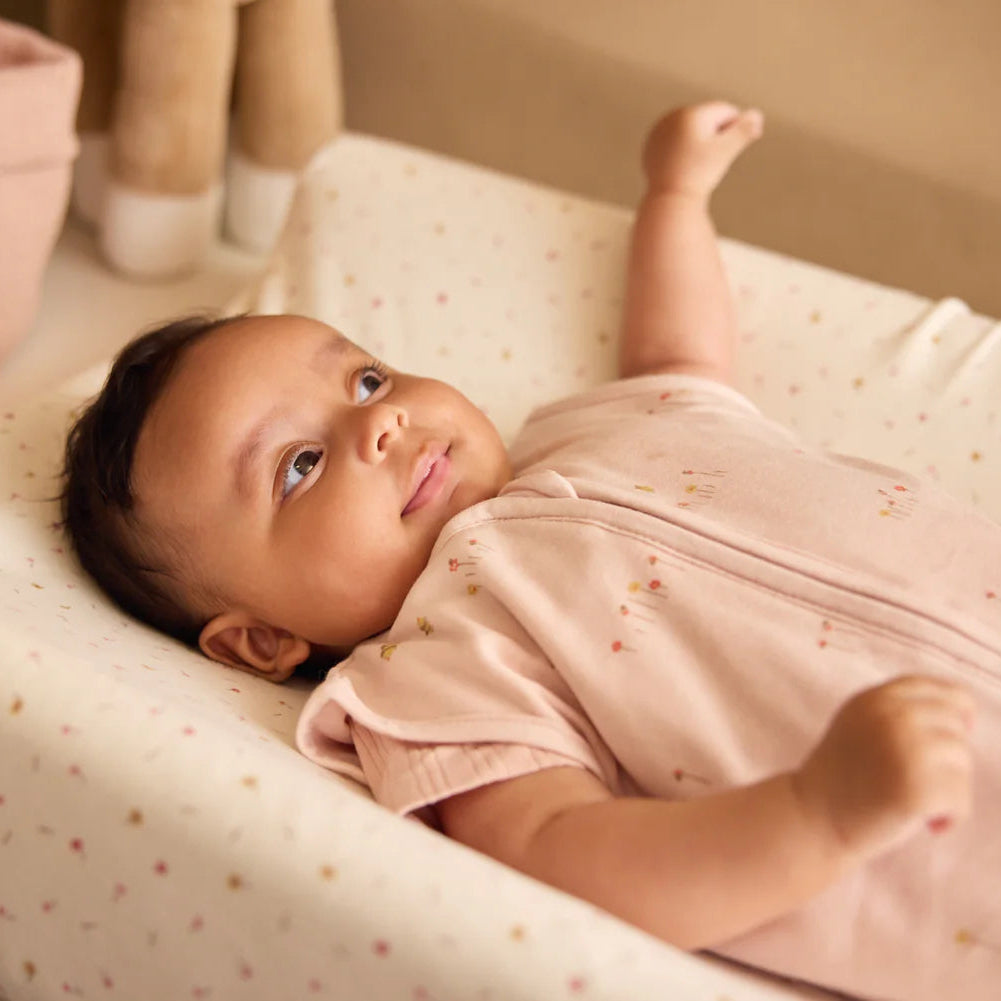 Baby lying on a changing table with a pink outfit