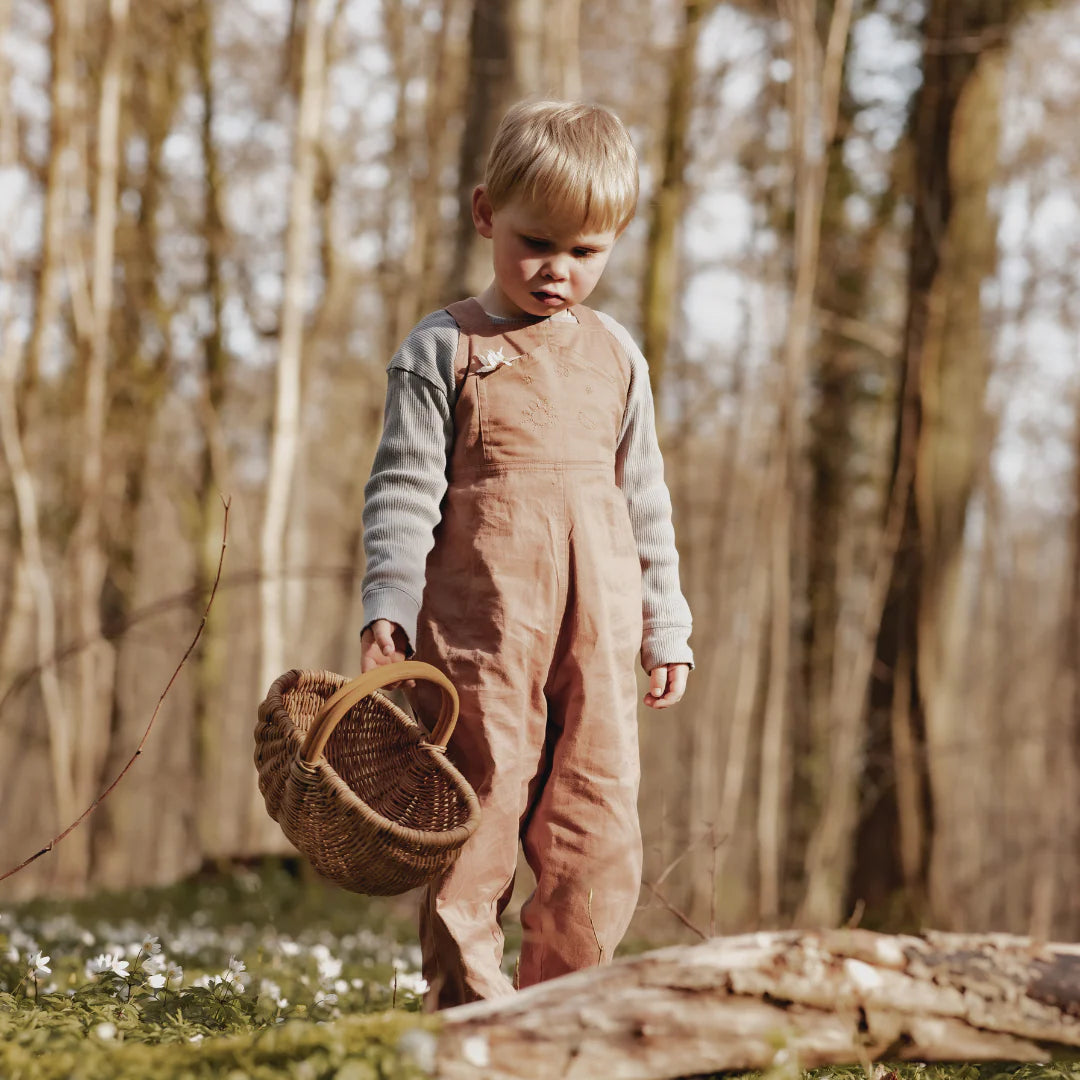 Child in a forest holding a woven basket